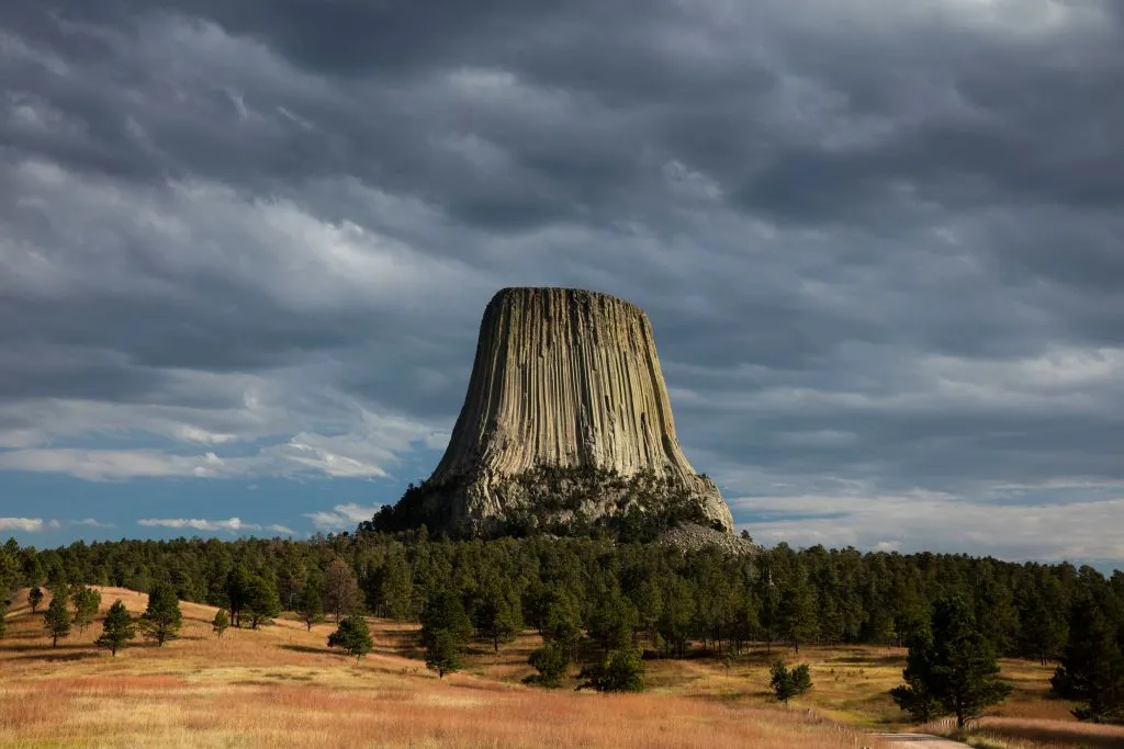 A panoramic view of Devil's Tower against a clear blue sky.