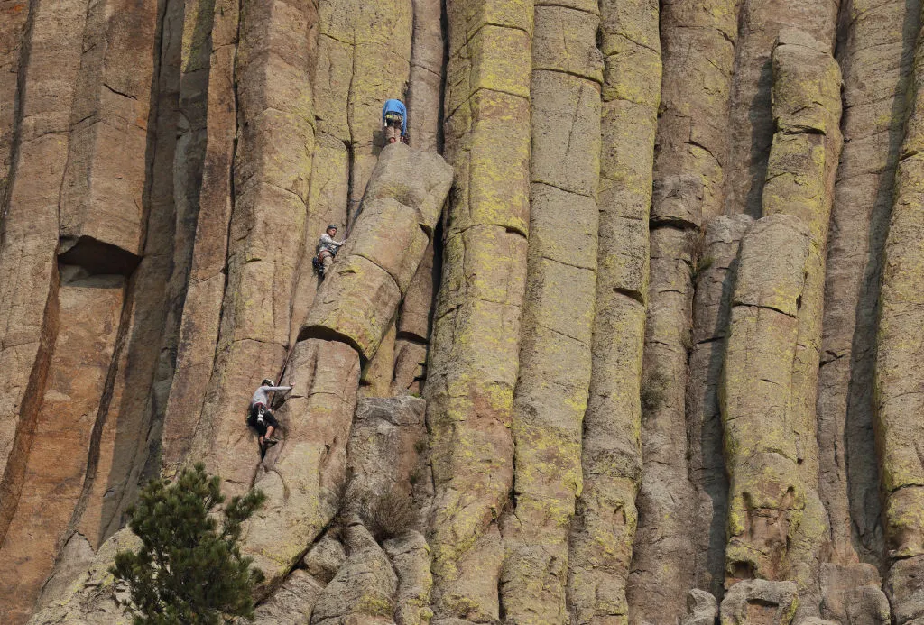 Rock climbers scaling the vertical face of Devil's Tower.